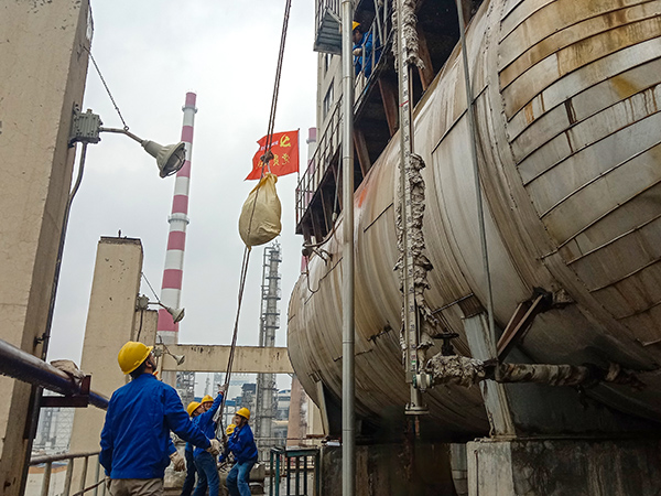 5月10日中午，在動(dòng)力車間三期工藝除氧器地面，黨員突擊隊(duì)隊(duì)員用滑輪往工藝除氧器平臺(tái)運(yùn)送鋼絲網(wǎng)，用以纏繞新填料.jpg