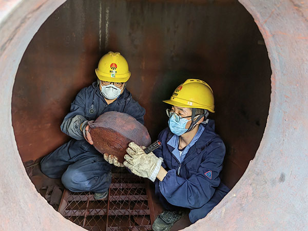 5月11日，動(dòng)力車間三期工藝除氧器內(nèi)部，黨員突擊隊(duì)隊(duì)員劉瑞斌和李震正在清理舊填料.jpg